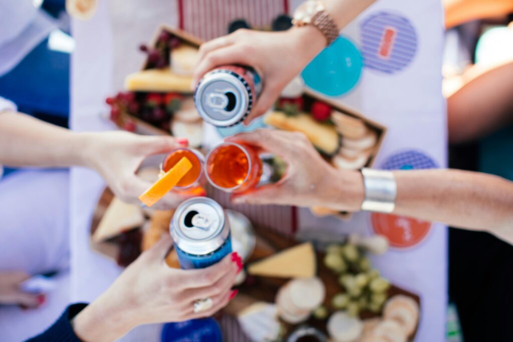 A lively outdoor gathering with friends toasting with beverages at a festive picnic.